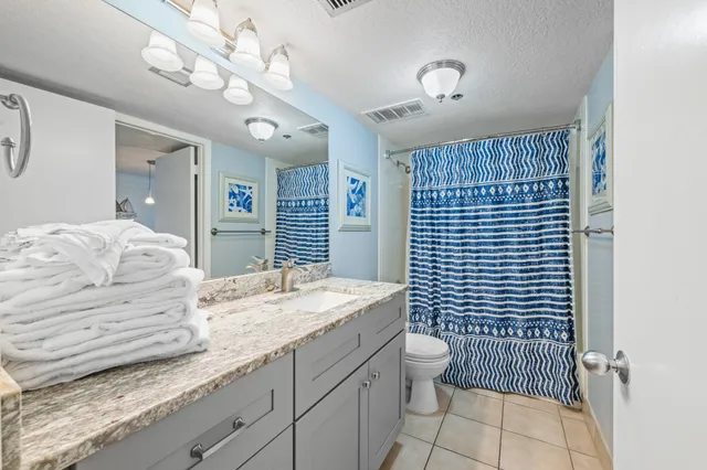 a bathroom with a granite countertop toilet sink and mirror