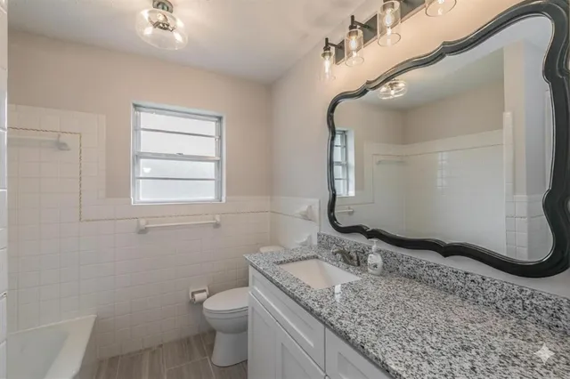 a bathroom with a granite countertop sink a toilet and a mirror
