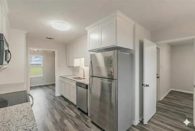 a kitchen with a refrigerator a stove and wooden floor