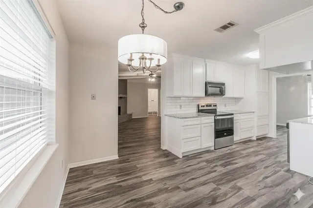 a large kitchen with cabinets wooden floor and stainless steel appliances