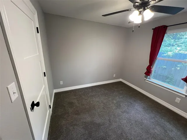 an empty room with a fireplace and a ceiling fan