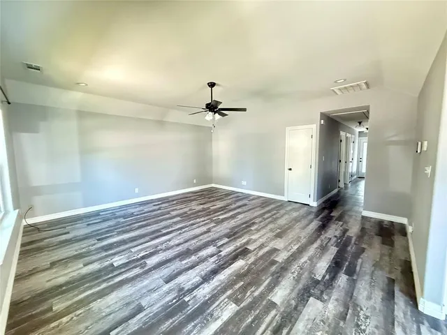 a view of an empty room with window and wooden floor