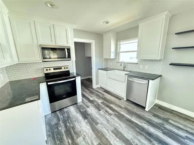 a kitchen with white cabinets and sink