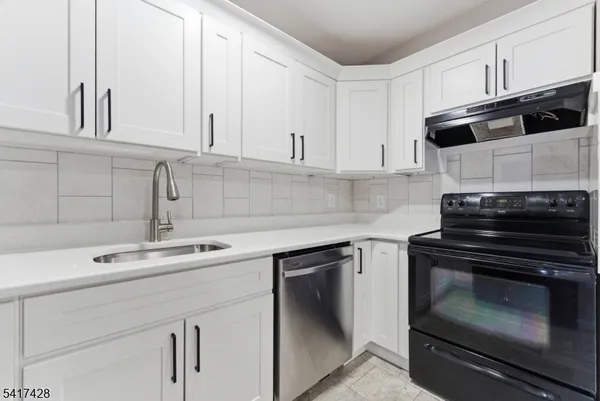 a kitchen with stainless steel appliances granite countertop white cabinets and a stove a oven with white countertops