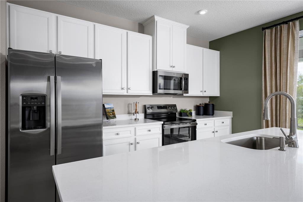 31391 Spanish Msn Road San Antonio, FL 33576 - Photo 6 of 26 a kitchen with stainless steel appliances a refrigerator sink and white cabinets