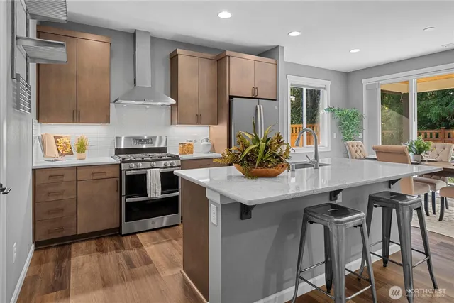 a kitchen with stainless steel appliances a sink a stove a refrigerator cabinets and dining table