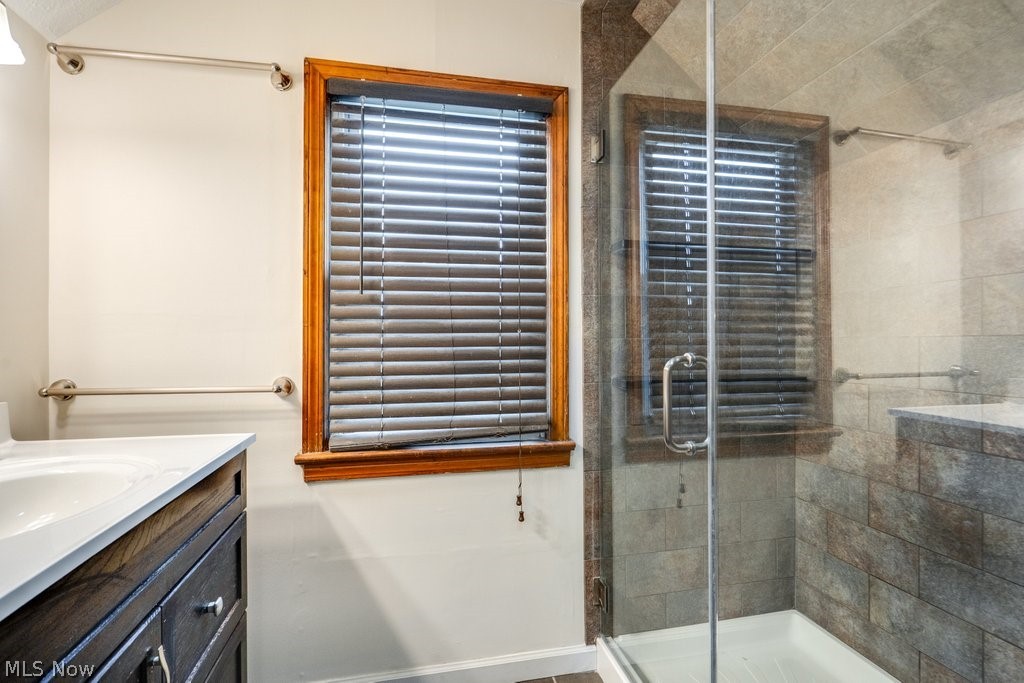 30000 Elgin Road Wickliffe, OH 44092 - Photo 20 of 30 Bathroom featuring a glass-enclosed shower, a vanity with an undermount sink and white countertop, a window with wood trim, and wall-mounted grab bars