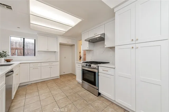 a kitchen with white cabinets and appliances
