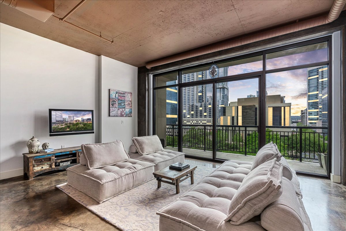 a living room with furniture a floor to ceiling window and a flat screen tv