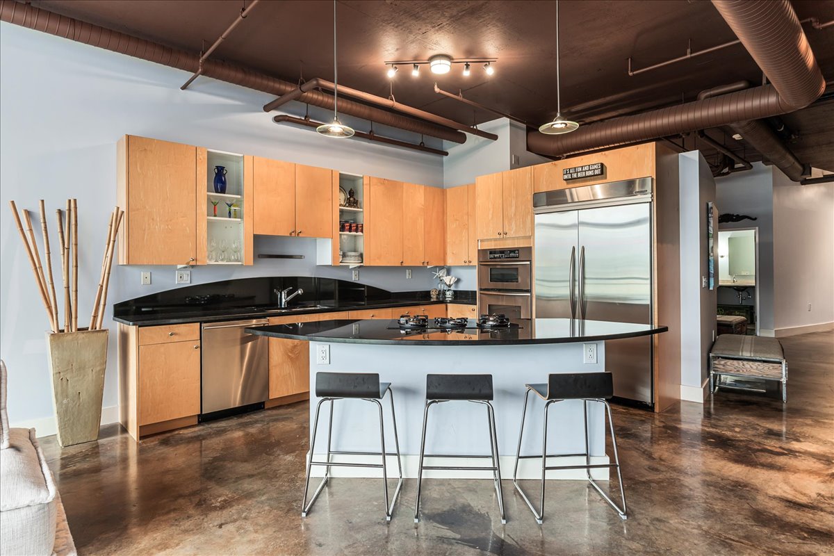 311 West 5th Street, Unit 703 Austin, TX 78701 - Photo 12 of 30 a kitchen with stainless steel appliances granite countertop a table chairs and wooden cabinets