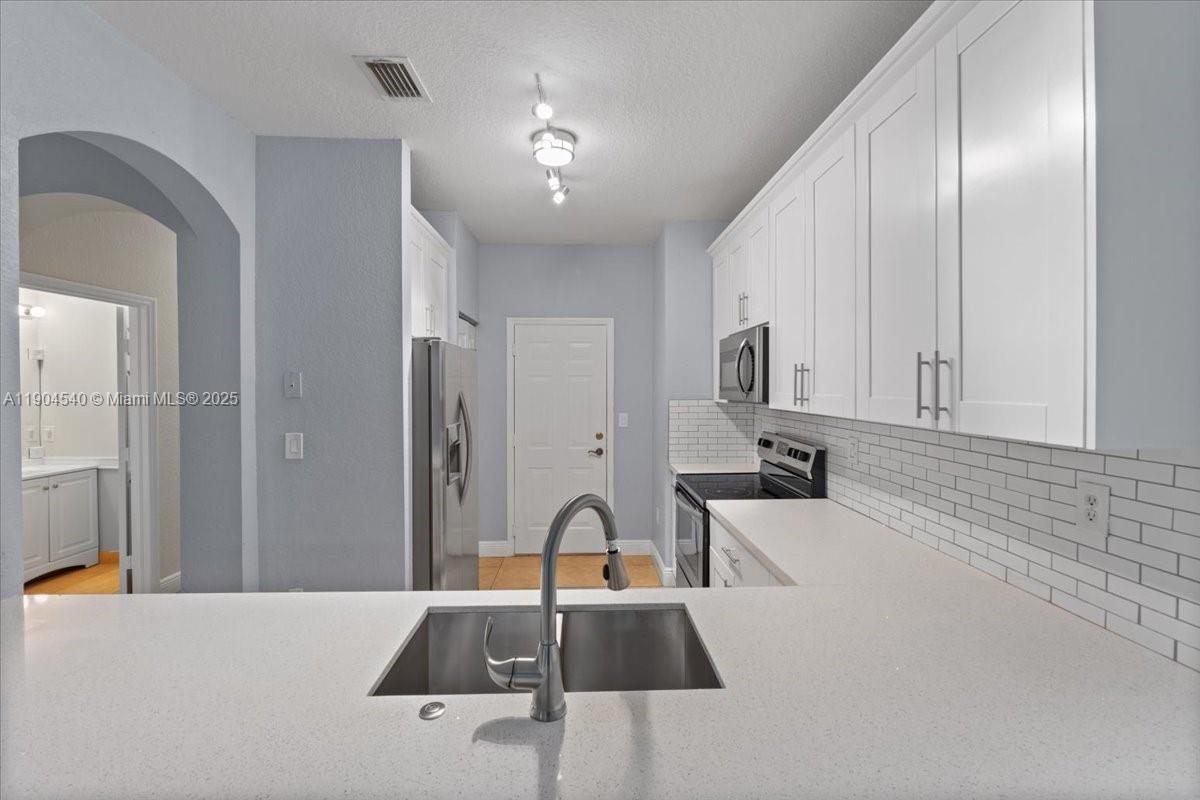 12720 Southwest 49th Court Miramar, FL 33027 - Photo 6 of 26 a kitchen with stainless steel appliances granite countertop a sink and refrigerator
