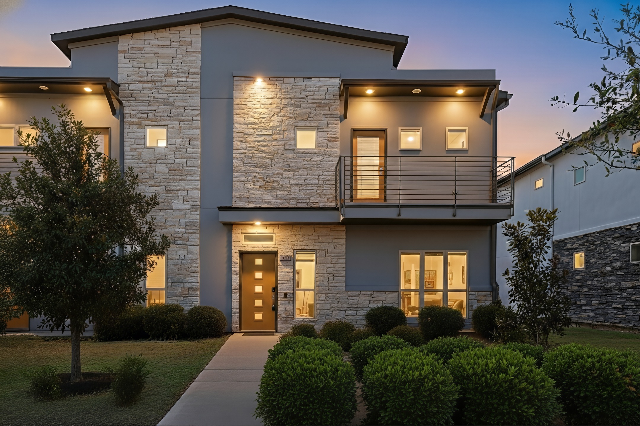 Contemporary home with a balcony, stone siding, and stucco siding