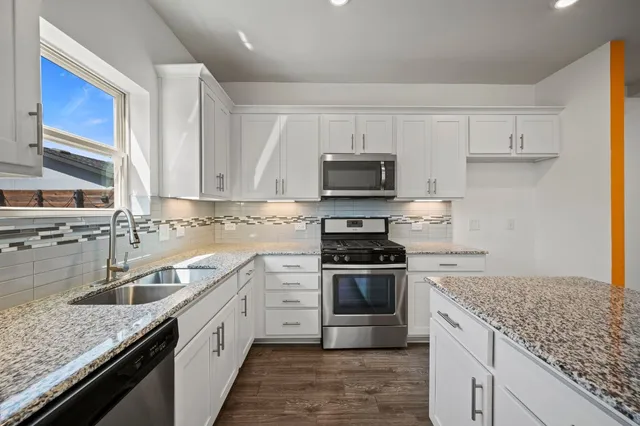 a kitchen with kitchen island granite countertop a sink stove and cabinets
