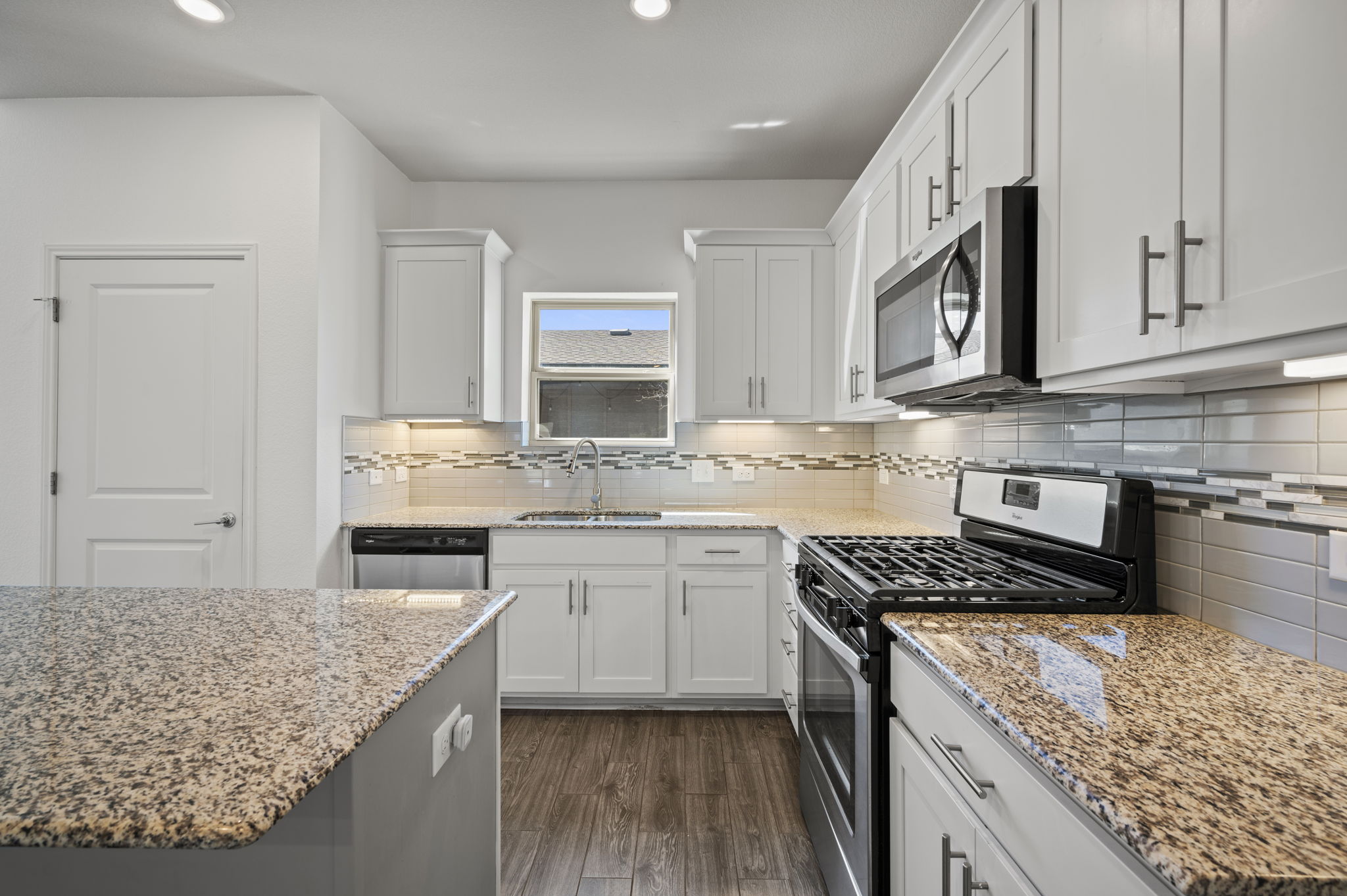 5809 Charles Merle Dr., Unit B Austin, TX 78747 - Photo 8 of 27 Kitchen with light stone countertops, dark wood-style flooring, a sink, stainless steel appliances, and white cabinets