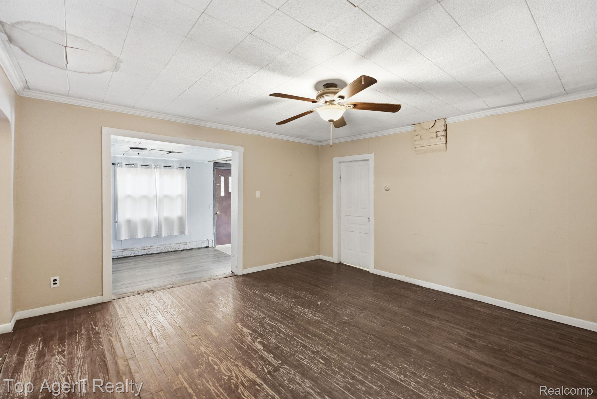 95 West Lapeer Road Peck, MI 48466 - Photo 11 of 33 Unfurnished room with ceiling fan, dark wood finished floors, ornamental molding, and a baseboard heating unit