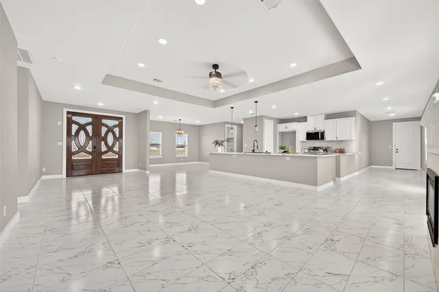 a view of an empty room and kitchen view with wooden floor