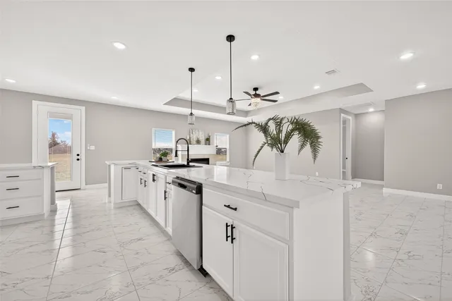 a view of a kitchen with kitchen island stainless steel appliances a sink a counter top space and cabinets