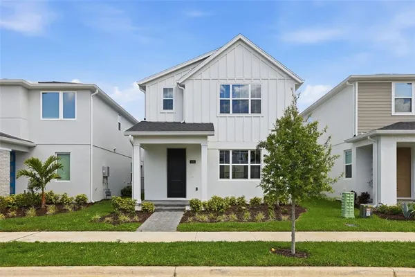 a view of a white house with potted plants and a yard