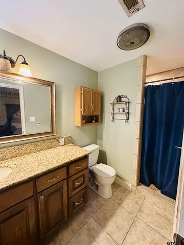 a bathroom with a granite countertop toilet sink and mirror