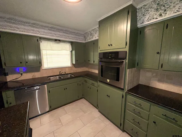 a kitchen with granite countertop a sink stainless steel appliances and cabinets