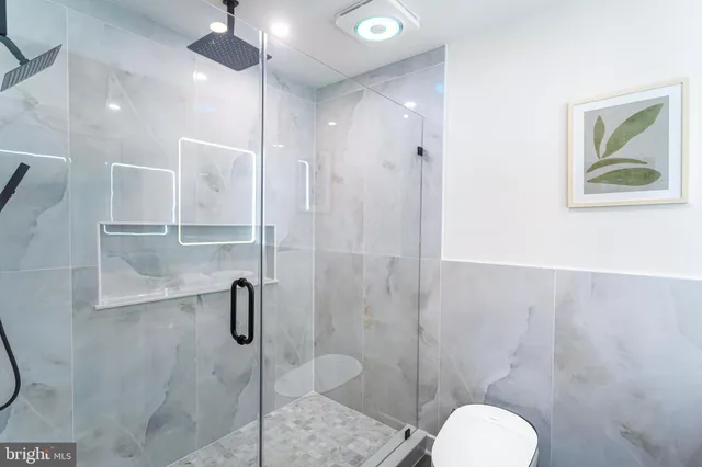 a bathroom with a shower sink mirror and toilet