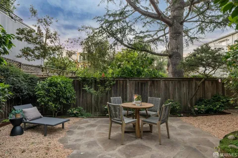 a view of backyard with table and chairs and a large tree