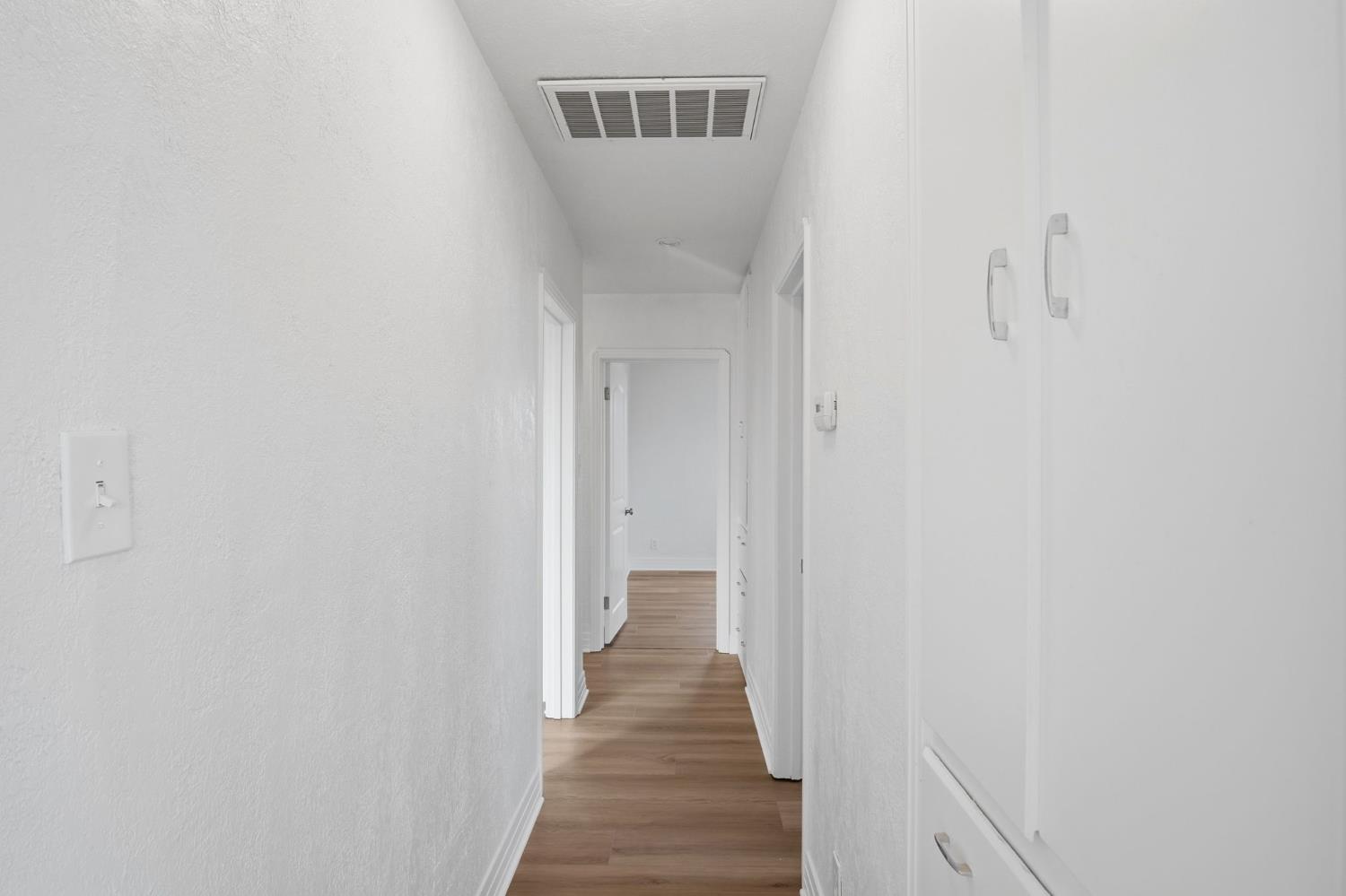 5333 Geer Road Turlock, CA 95382 - Photo 17 of 37 a view of a hallway with wooden floor and a bathroom