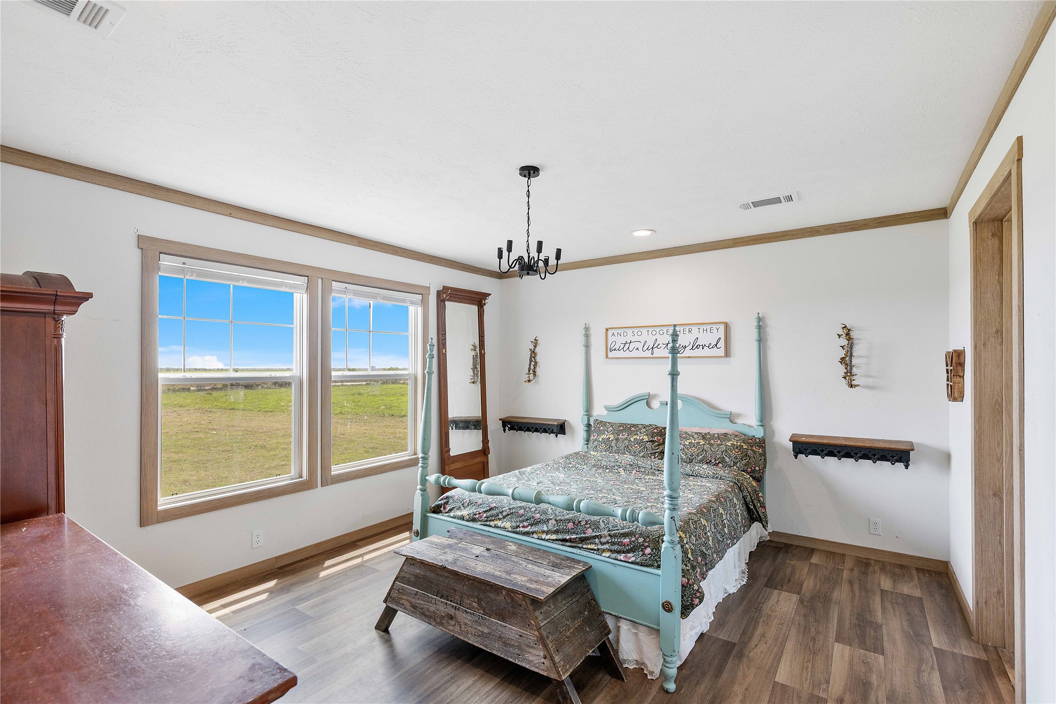 21550 Wilber Road Winnie, TX 77665 - Photo 16 of 28 a bedroom with a large bed and a chandelier