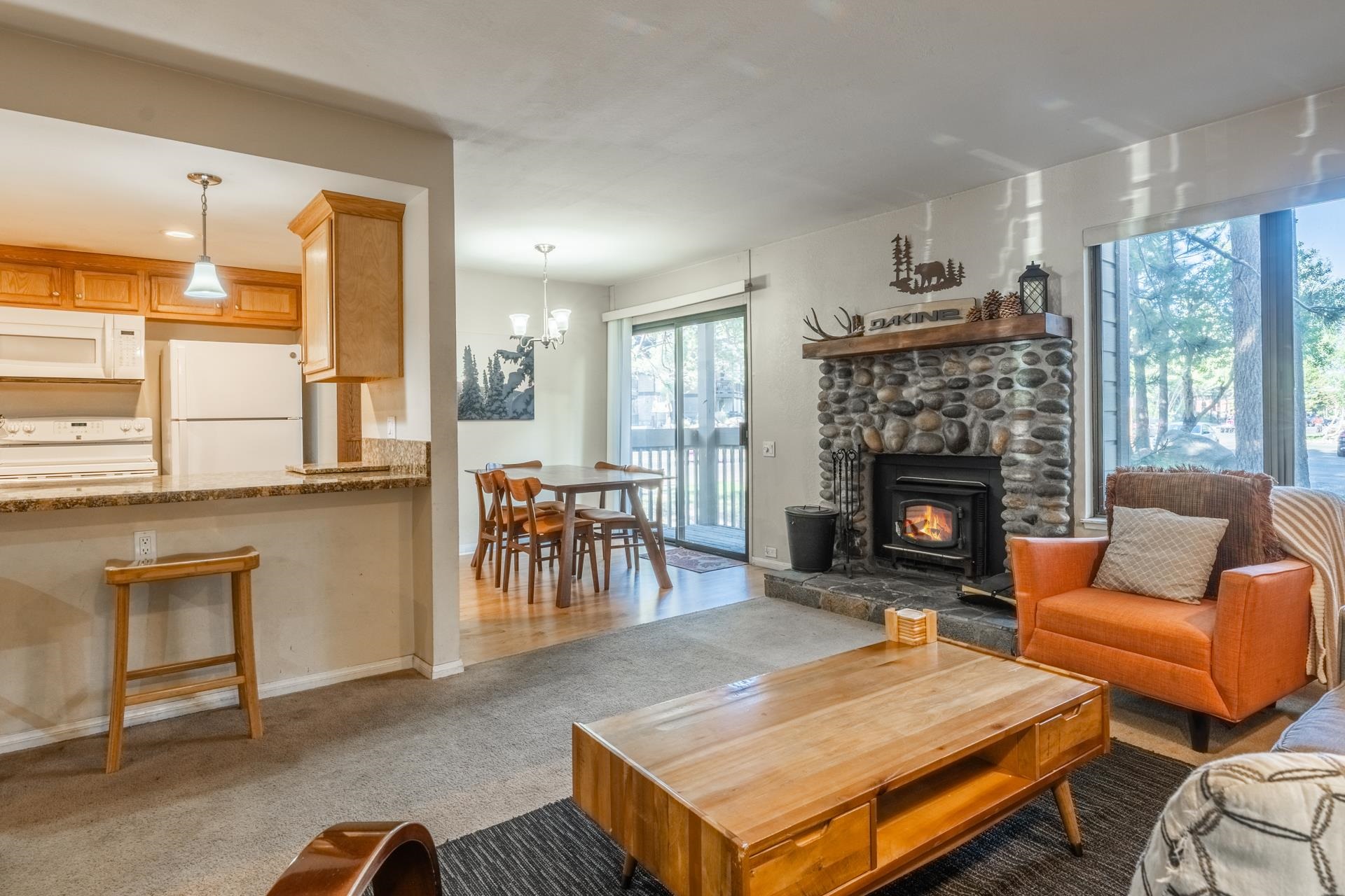 Living area with a chandelier, light carpet, and a stone fireplace