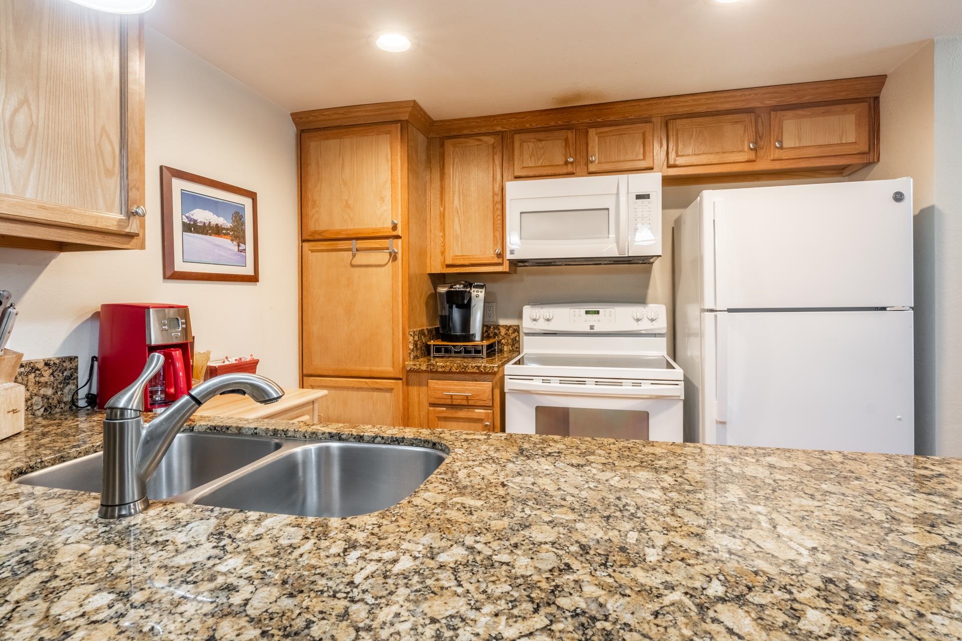 2113 Meridian Boulevard, Unit 141 Mammoth Lakes, CA 93546 - Photo 11 of 23 Kitchen featuring white appliances, light stone countertops, brown cabinetry, and recessed lighting