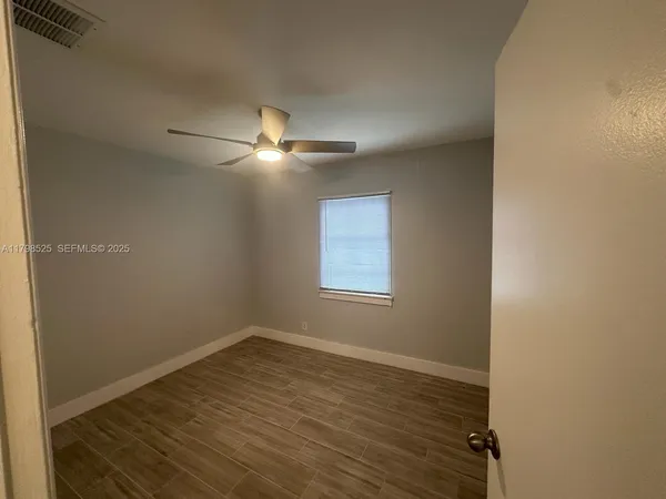 en empty room with wooden floor and fan