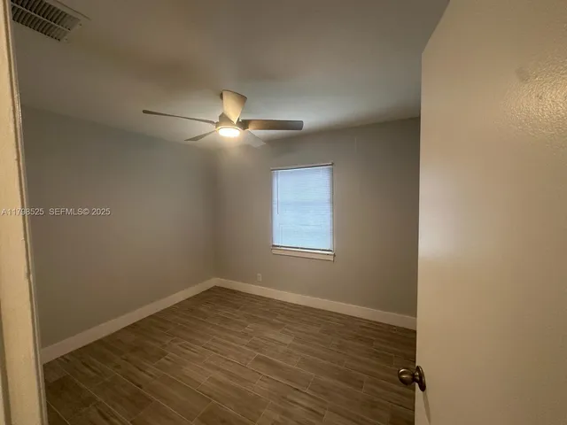 en empty room with wooden floor and fan