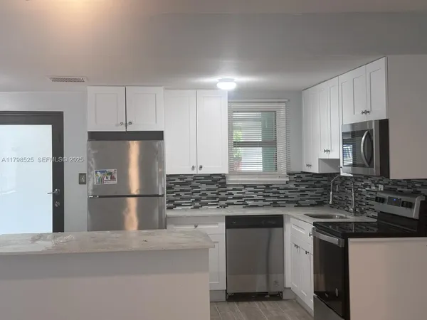 a kitchen with kitchen island a counter appliances a sink and cabinets