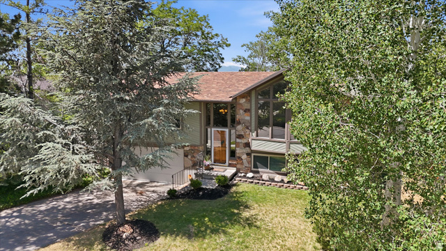 8938 Manchester Lane Sandy, UT 84093 - Photo 46 of 50 Split-level residence featuring a prominent stone facade, a multi-pane picture window, and a brown shingle roof