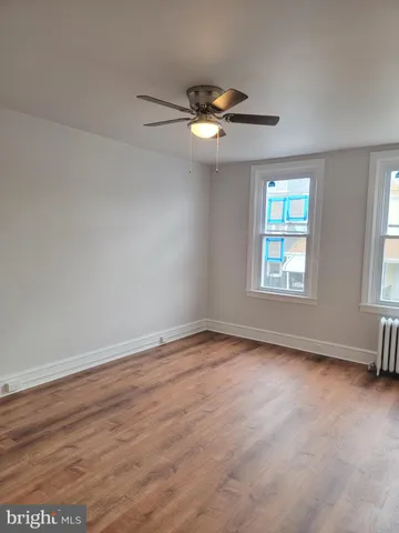 a view of empty room with wooden floor and fan
