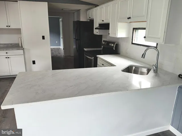 a kitchen with stainless steel appliances kitchen island granite countertop a refrigerator a sink a stove and white cabinets