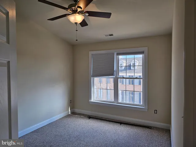 an empty room with ceiling fan and window