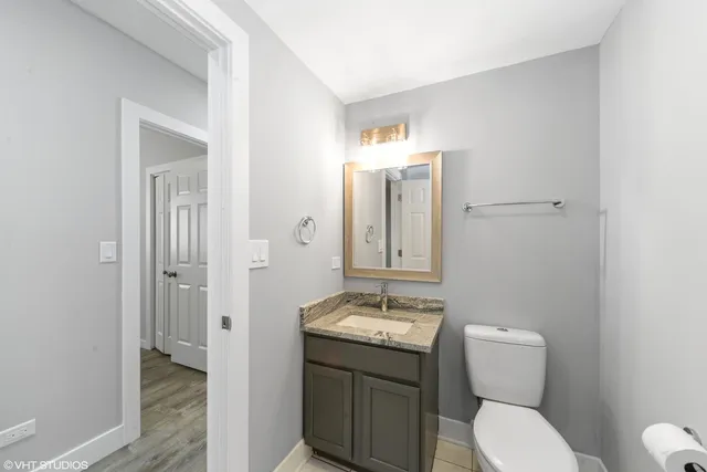 a bathroom with a granite countertop toilet sink and mirror