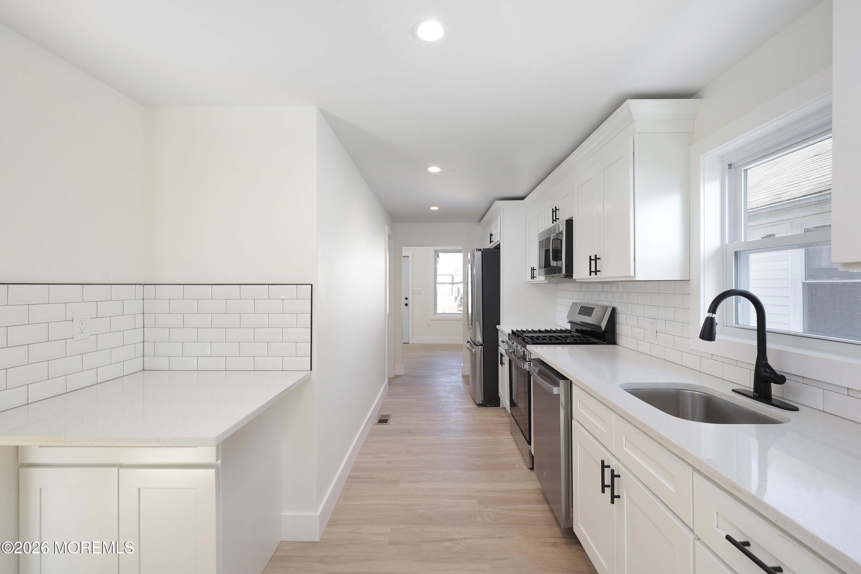 1216 8th Avenue Neptune, NJ 07753 - Photo 12 of 29 a kitchen with white cabinets a sink and dishwasher