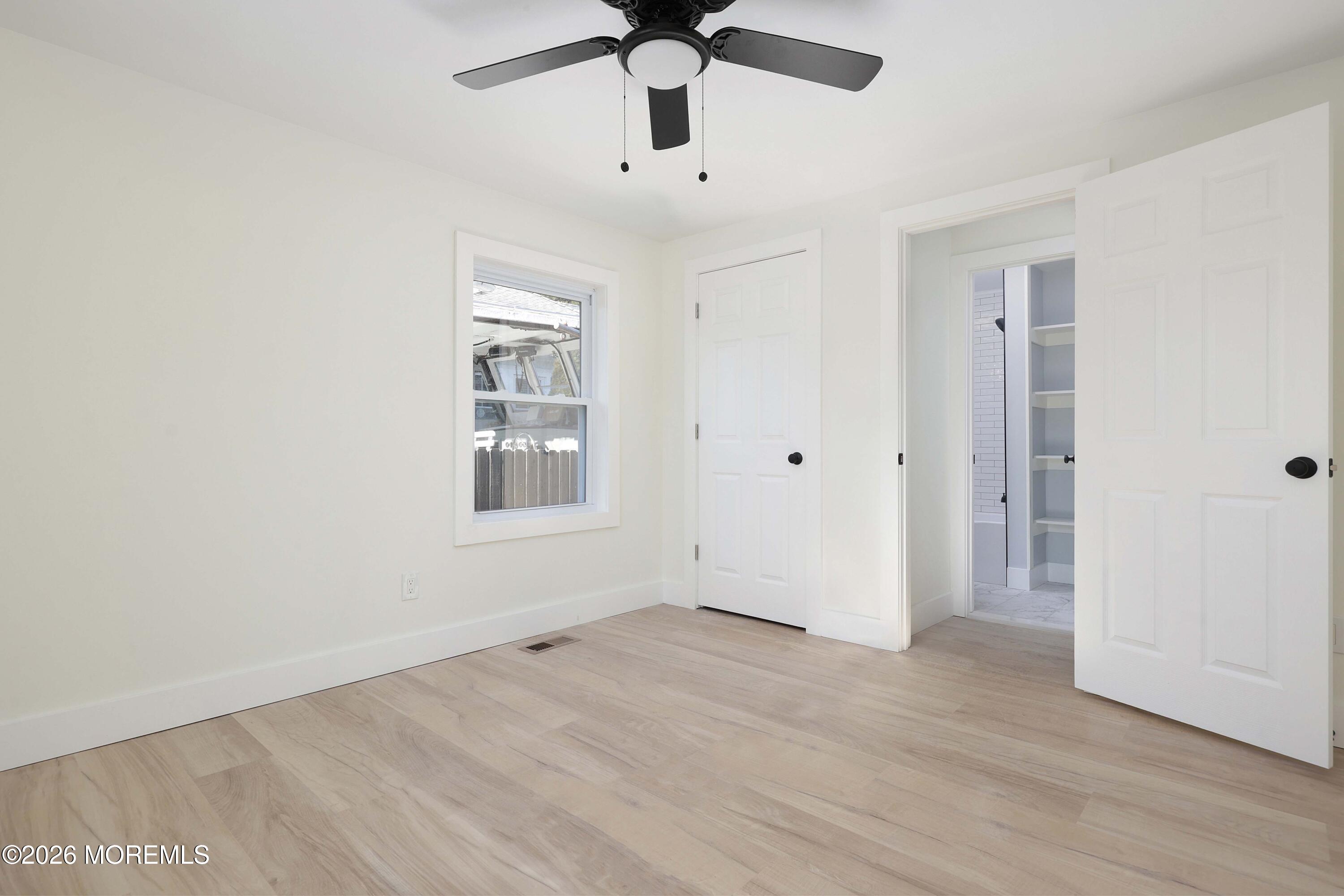 1216 8th Avenue Neptune, NJ 07753 - Photo 24 of 29 an empty room with wooden floor ceiling fan and windows
