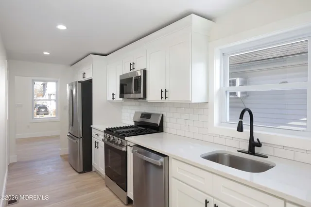 a kitchen with stainless steel appliances granite countertop white cabinets a stove top oven a sink and dishwasher