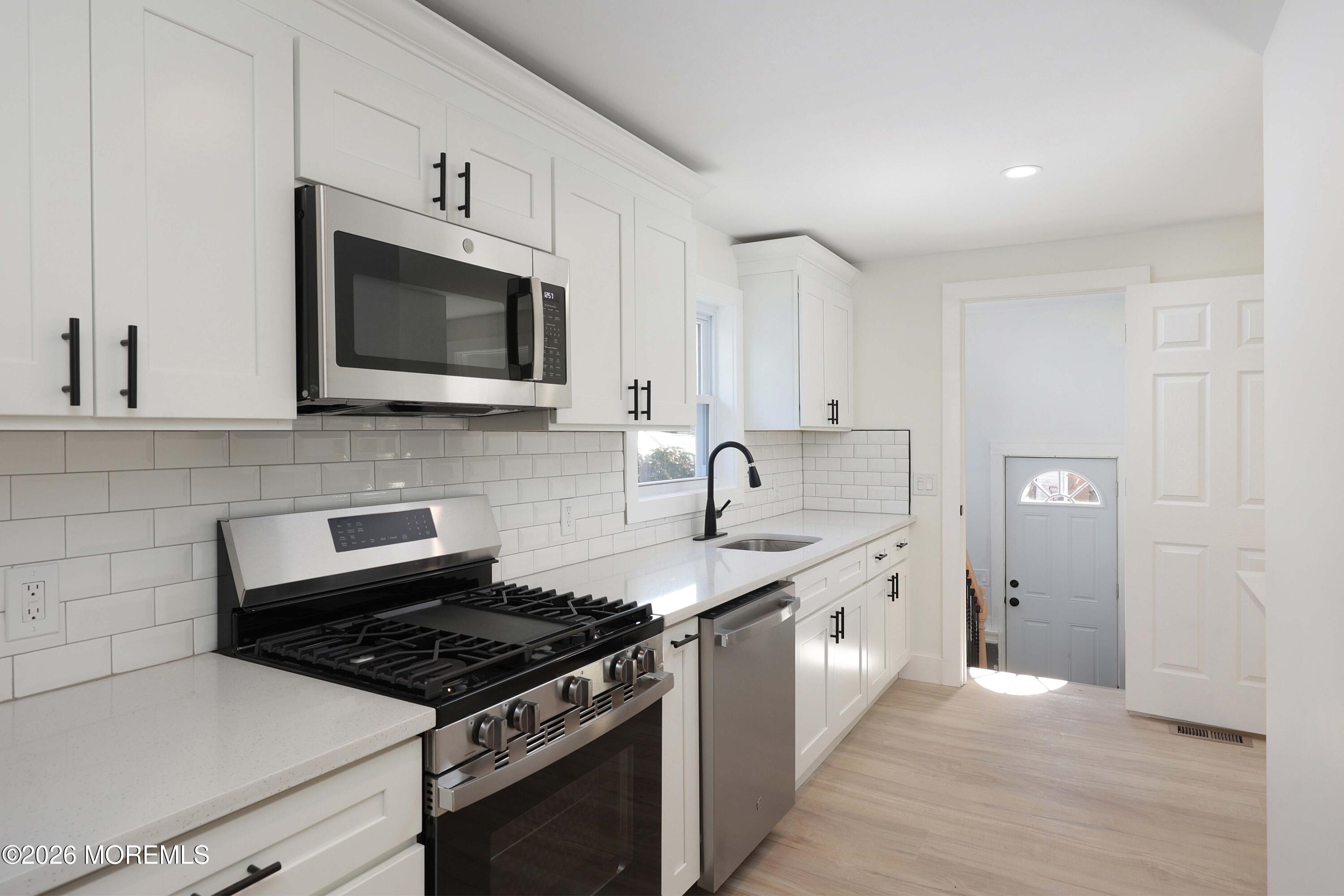 1216 8th Avenue Neptune, NJ 07753 - Photo 8 of 29 a kitchen with stainless steel appliances granite countertop white cabinets a stove top oven a sink and dishwasher