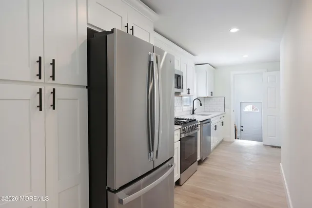 a kitchen with white cabinets a sink and dishwasher
