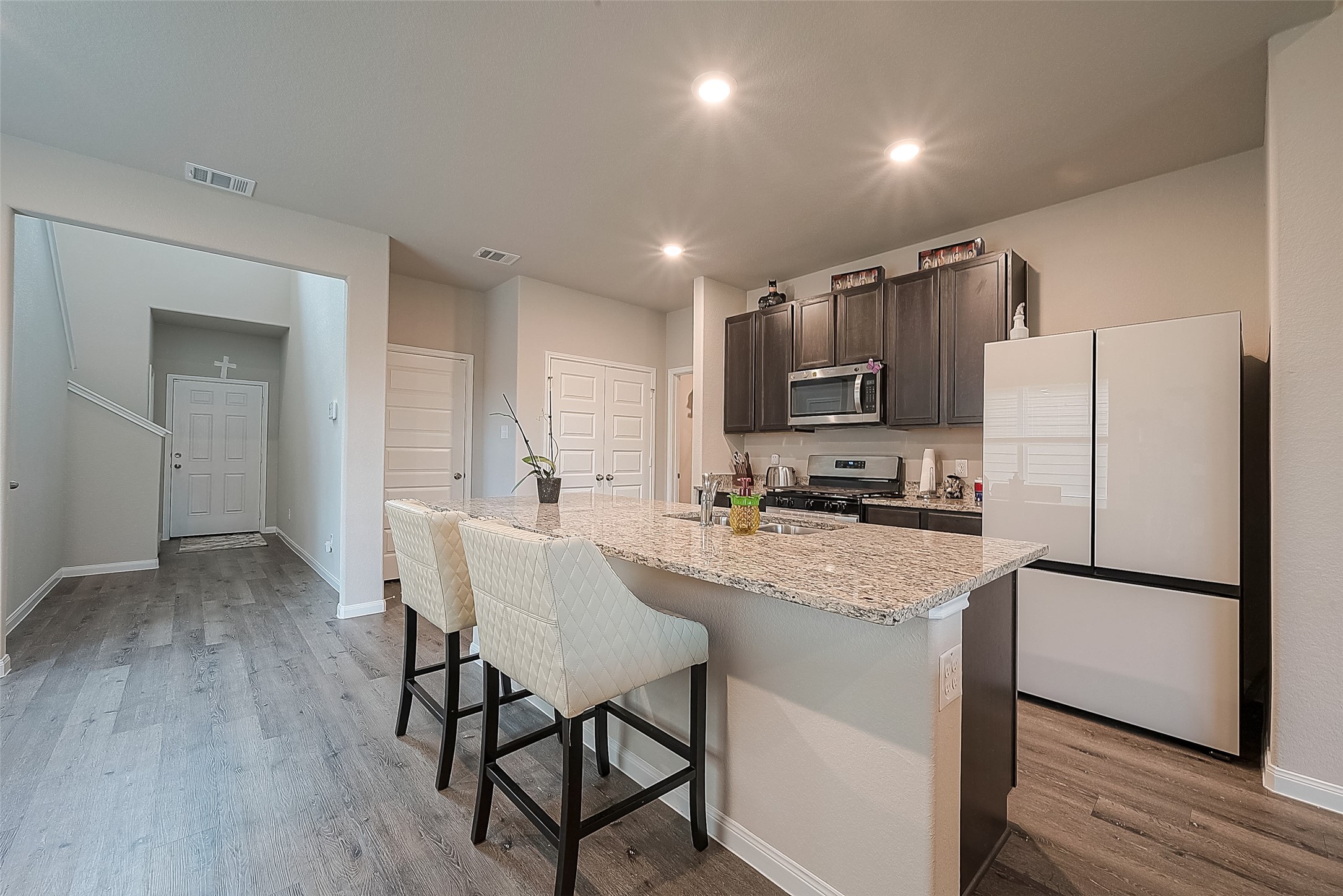 1317 Mount Bassie Trail Conroe, TX 77301 - Photo 12 of 50 a kitchen with stainless steel appliances granite countertop a refrigerator a stove top oven a sink dishwasher and white cabinets with wooden floor