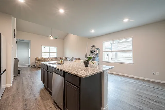 a kitchen with granite countertop a refrigerator stove and sink