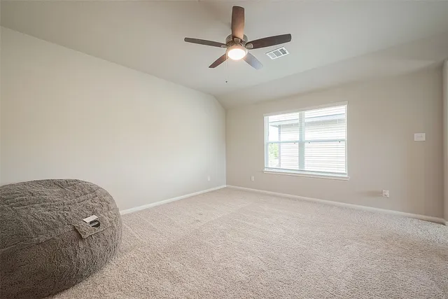 an empty room with a chandelier fan and windows
