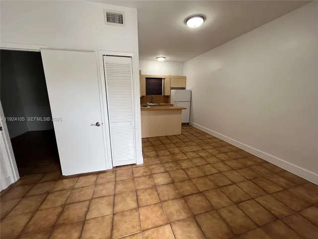 a view of a refrigerator in kitchen and an empty room