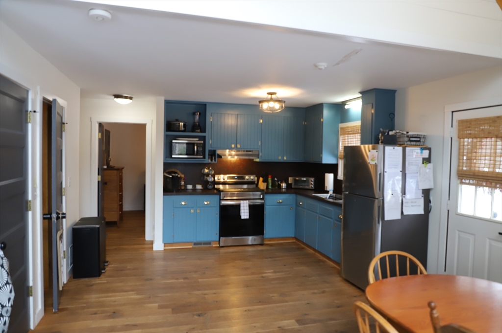 6 Path Road Tolland, MA 01034 - Photo 5 of 36 a kitchen with stainless steel appliances granite countertop a refrigerator a stove and a sink with wooden floor
