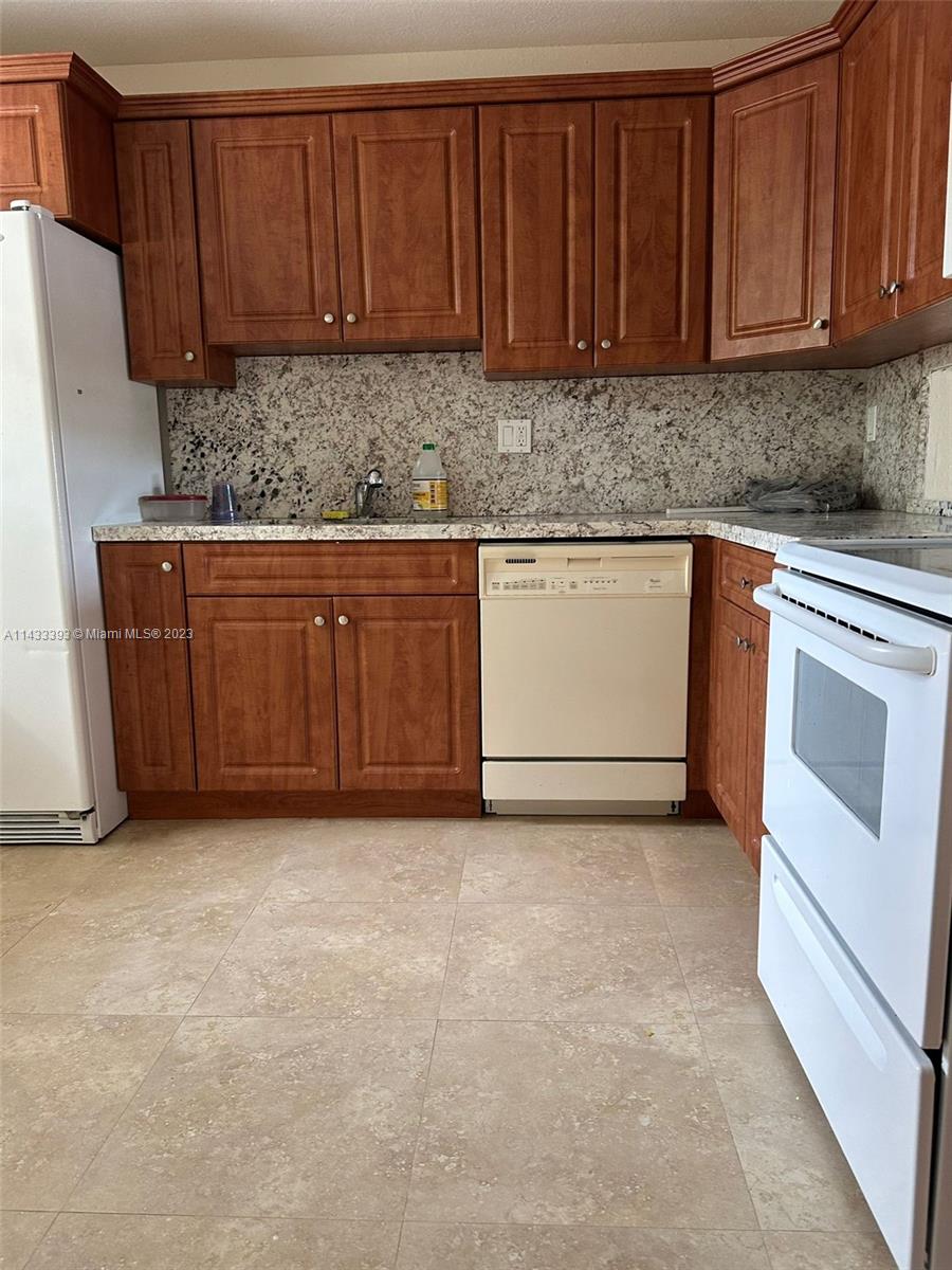 8327 Southwest 137th Avenue, Unit 8327 Miami, FL 33183 - Photo 3 of 31 a kitchen with granite countertop a sink stove and cabinets