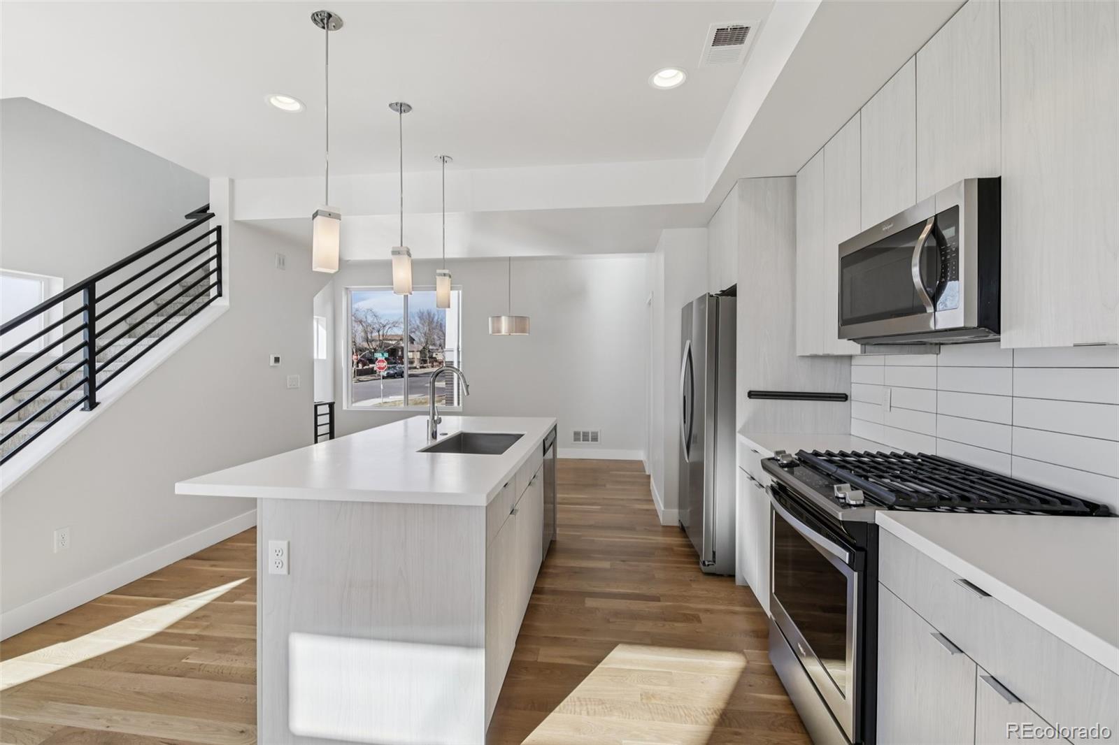 1274 Quitman Street, Unit 6 Denver, CO 80204 - Photo 12 of 50 a kitchen with stainless steel appliances kitchen island a sink stove and microwave